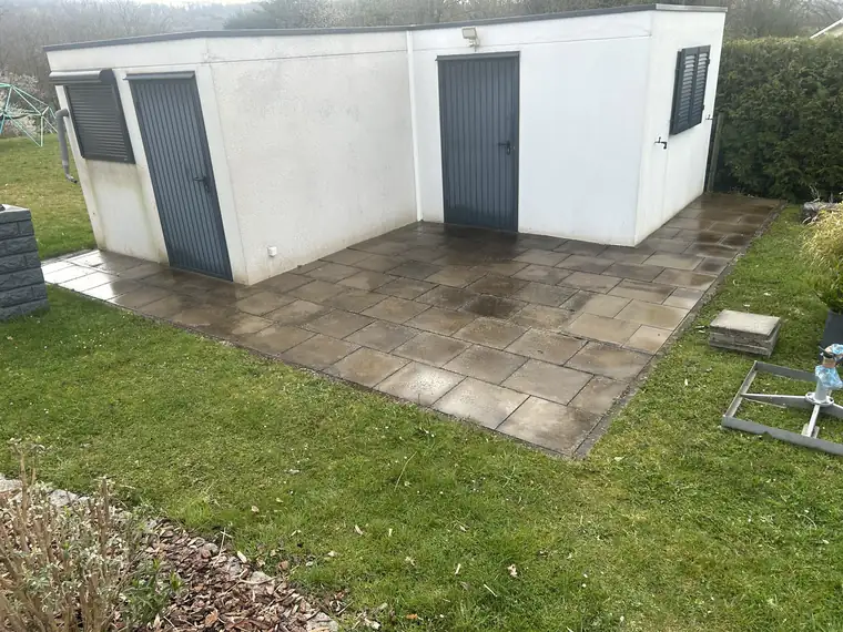 Terrasse am Gartenhaus mit dunklen Platten vor der Reinigung