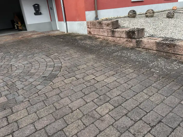 Hof mit Natursteinmauer und Flechten auf dem Pflaster vor der Reinigung