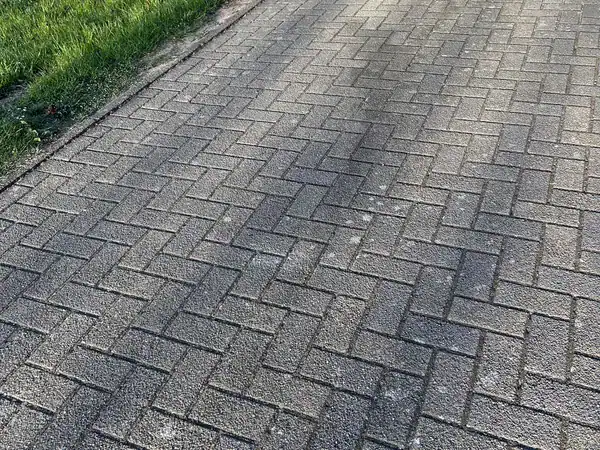 Dunkle Ölspur auf einer Pflastereinfahrt vor der Reinigung