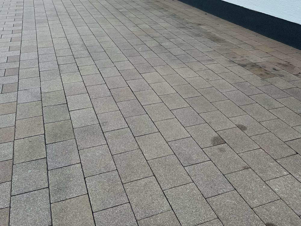 Vergraute Einfahrt aus rotem Pflaster vor der Reinigung